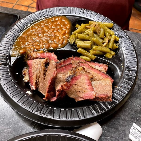 Smokin’ Jim's House of Bar-B-Q brisket, baked beans, and green beans on a black plate.