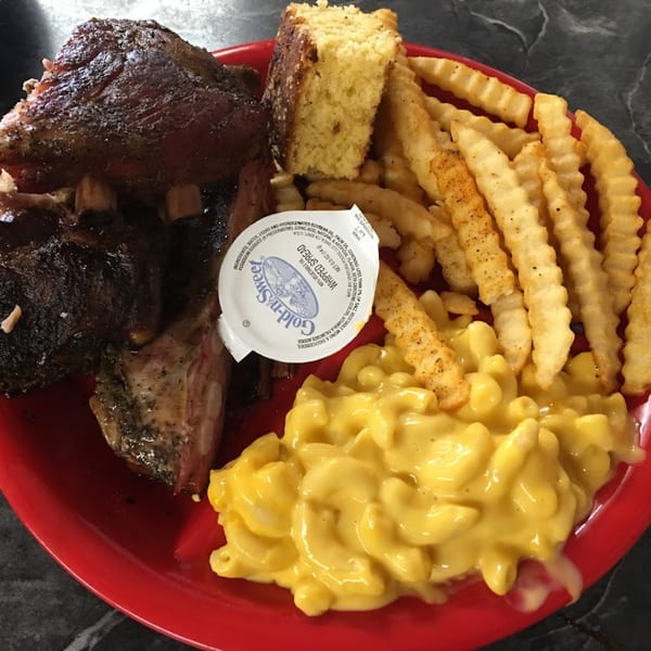 A Smokin’ Jim's House of Bar-B-Q plate with ribs, cornbread, crinkle-cut fries, and mac and cheese.