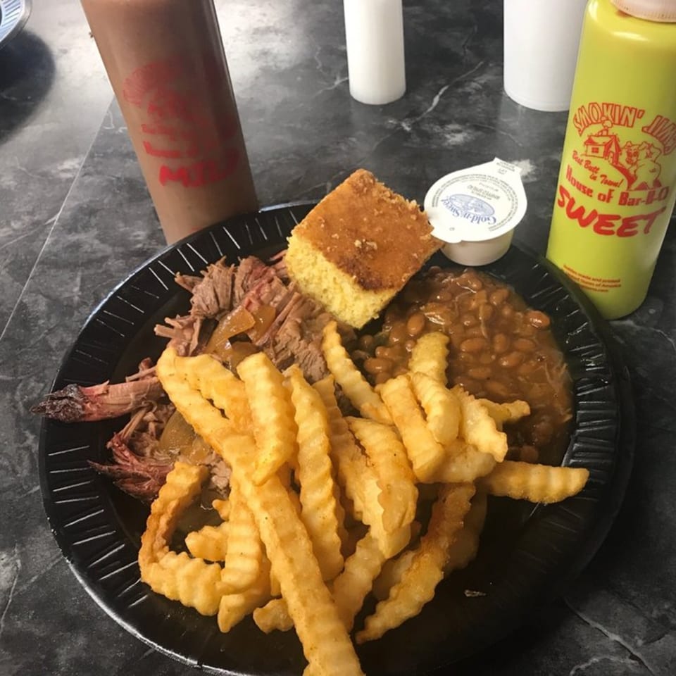 A Smokin' Jim's House of Bar-B-Q plate with brisket, crinkle fries, baked beans, and cornbread.